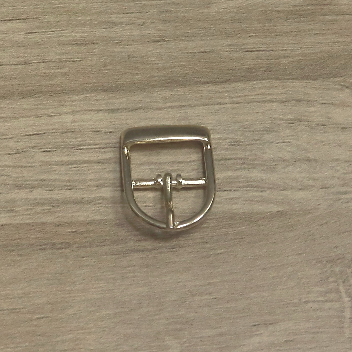 Brass-plated D shape buckle with the heel bar at the top and the pin resting on the curved end