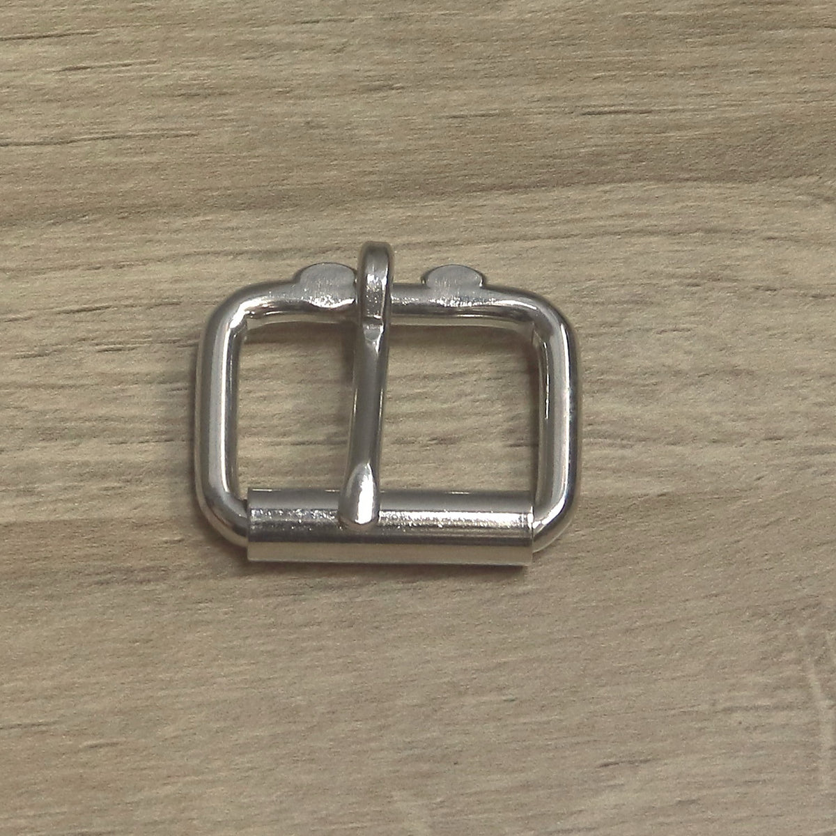 Nickel-plated heavy wire roller buckle from above, roller along the bottom bar and pin pointing down onto it