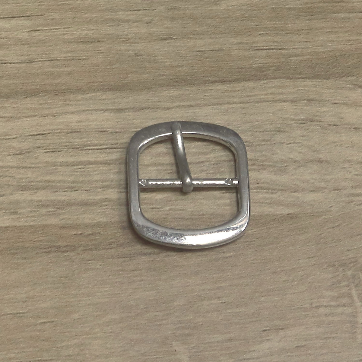 Nickel-plated oval buckle upright, with the pin swung over to the opposite side of the centre bar
