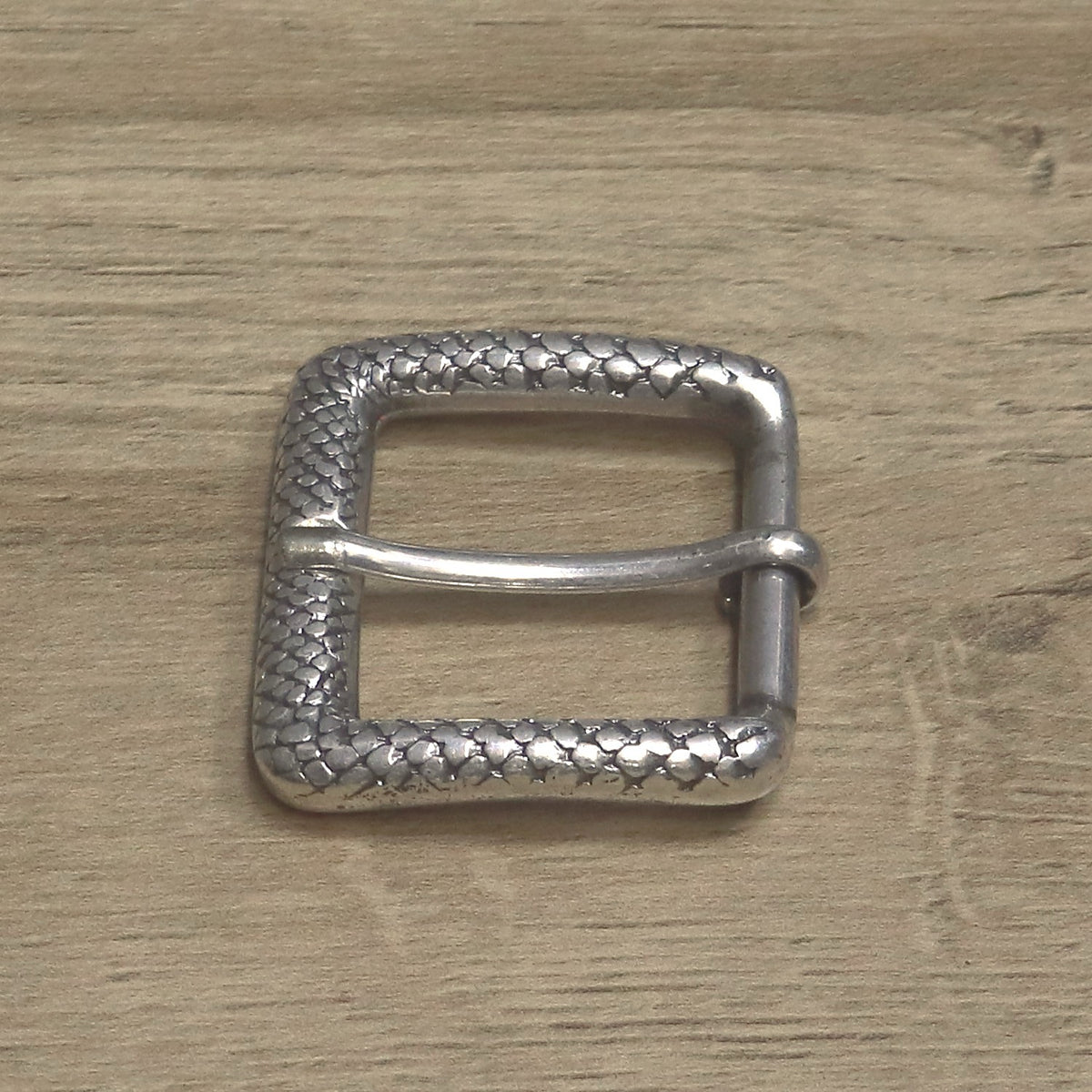 Textured roller buckle on its side, showing the roller under the pin