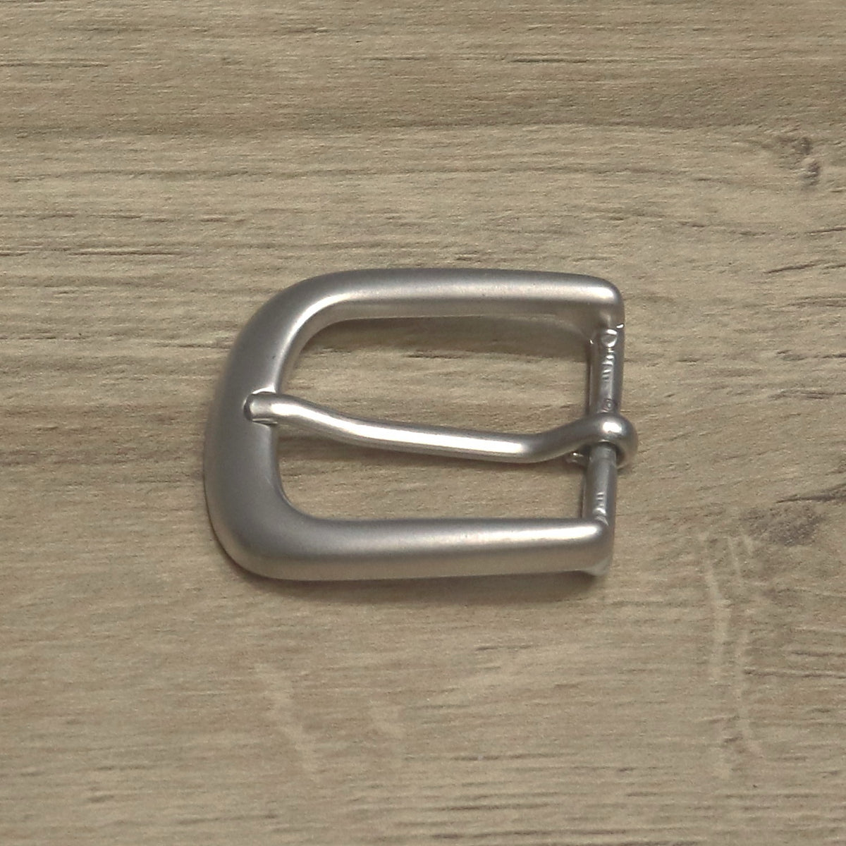 Brushed antique nickel belt buckle angled, pin resting on the rounded front bar