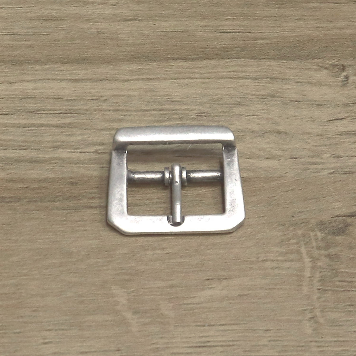Cast centre bar buckle from above, showing the pin hinged on the centre bar