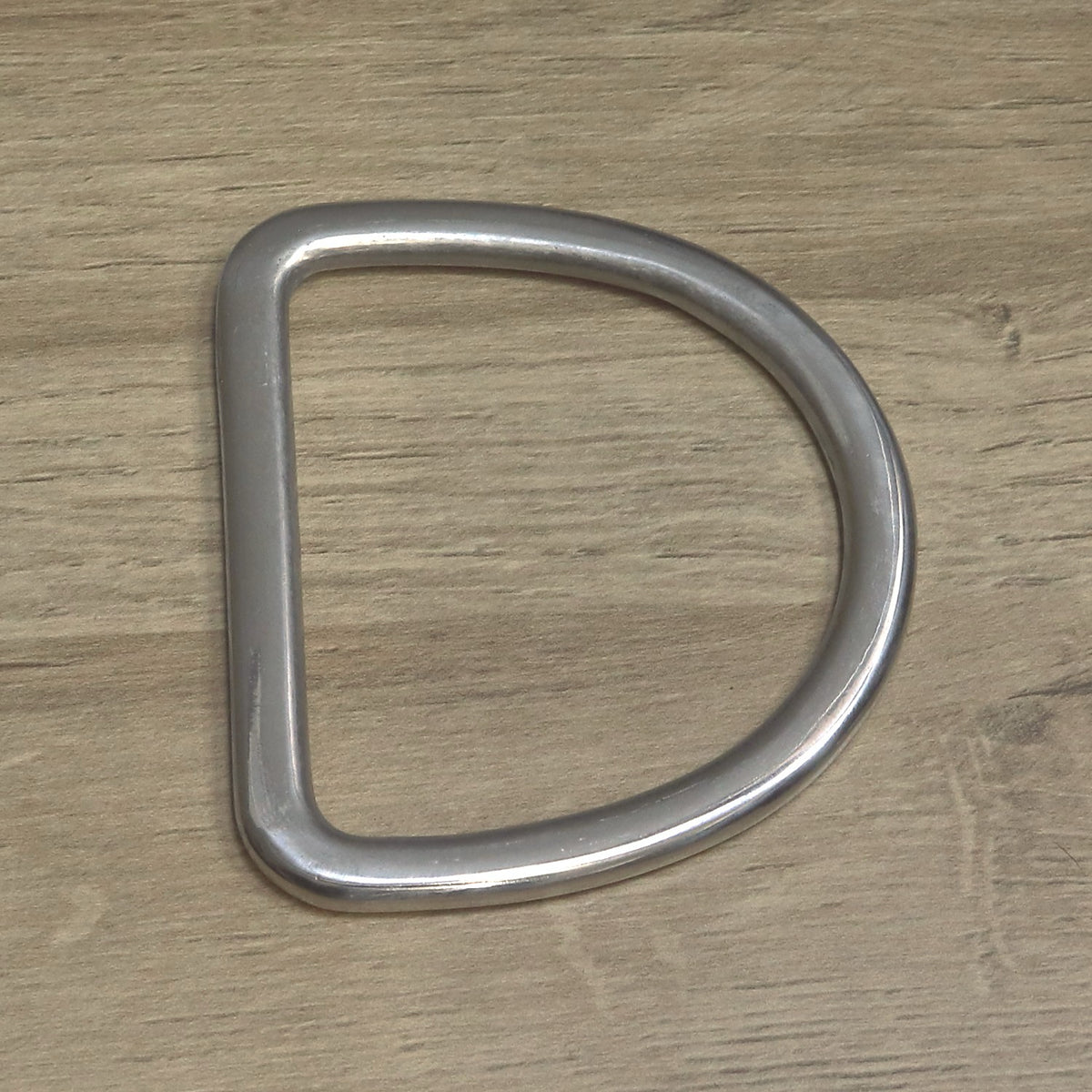 Large nickel-plated D ring for a 75mm strap, rounded curve with a flat straight bar on the left