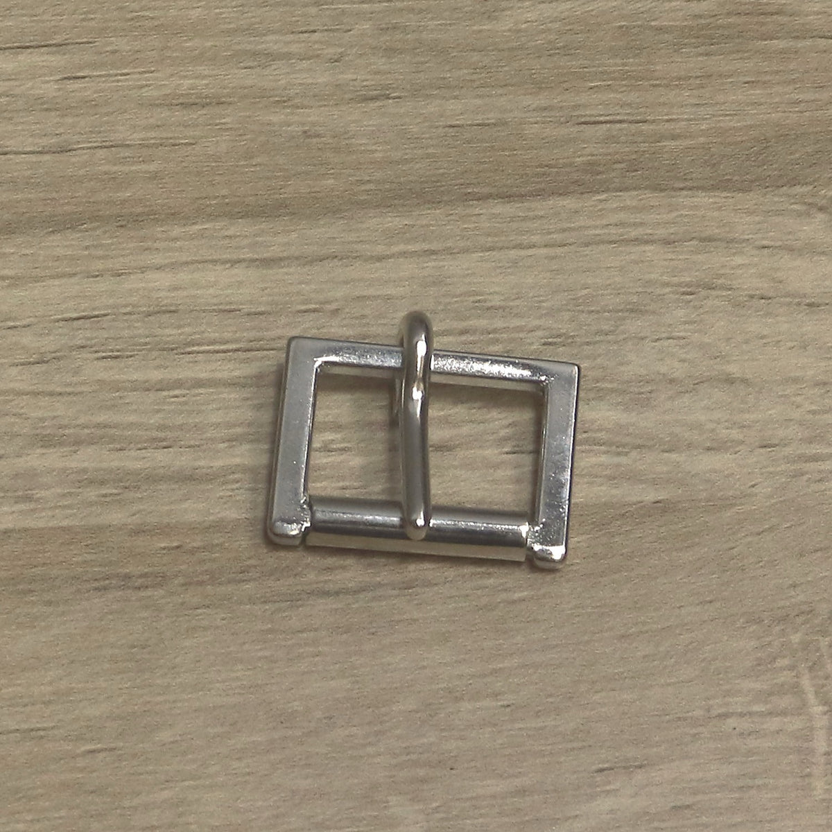 Nickel-plated cast buckle from above, roller along the bottom and pin pointing up
