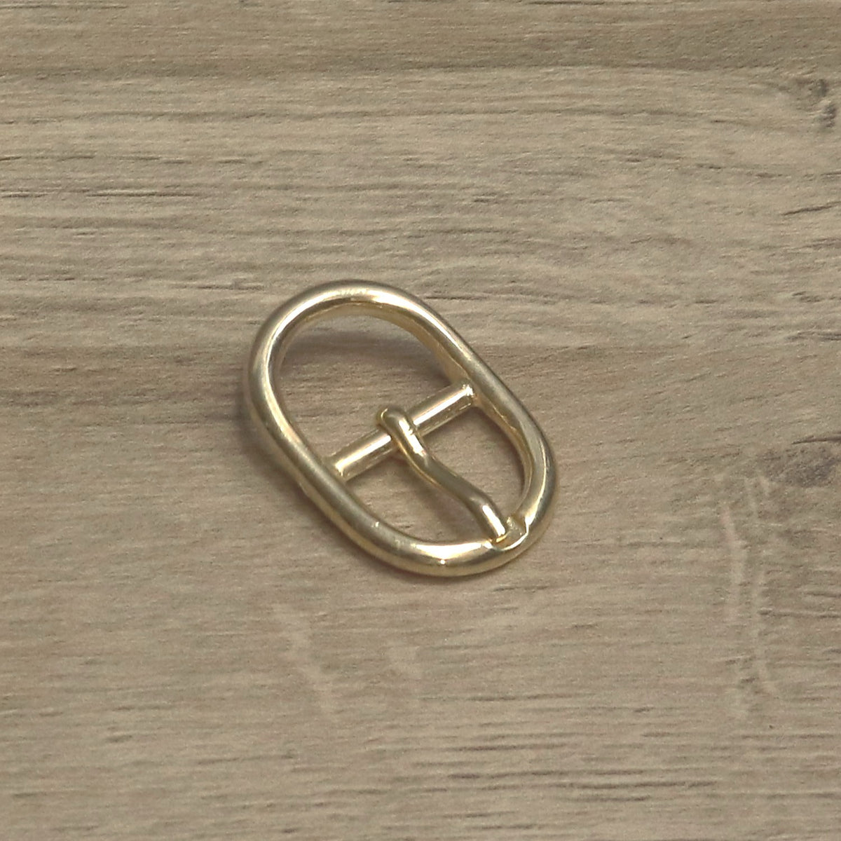 Brass-plated centre bar buckle, angled to show the pin and bar