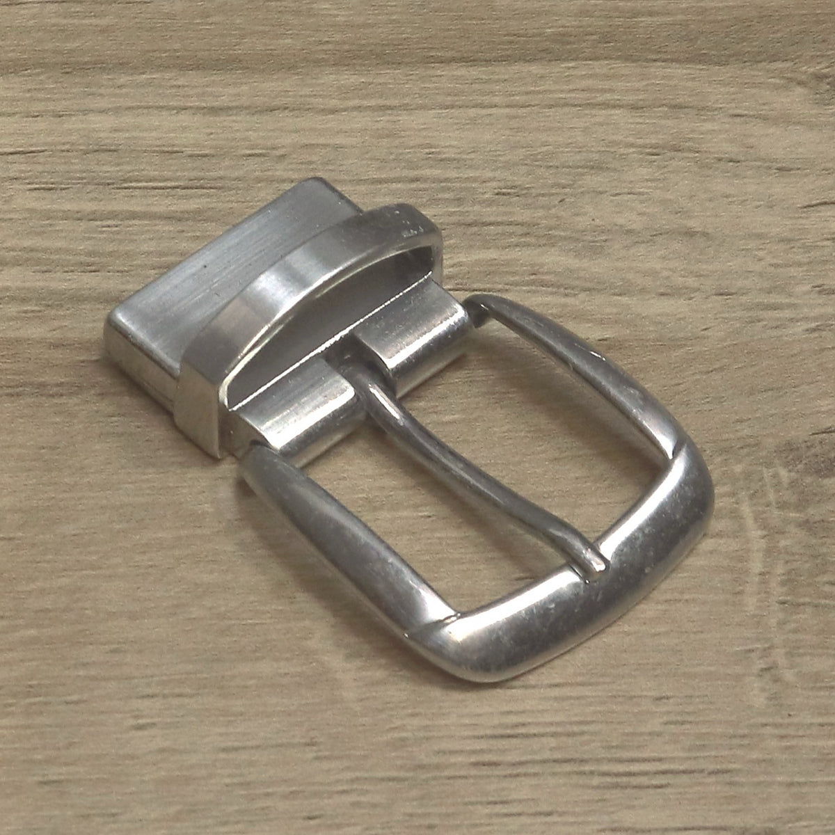 Nickel clamp buckle angled to show the pin and the hinged clamp