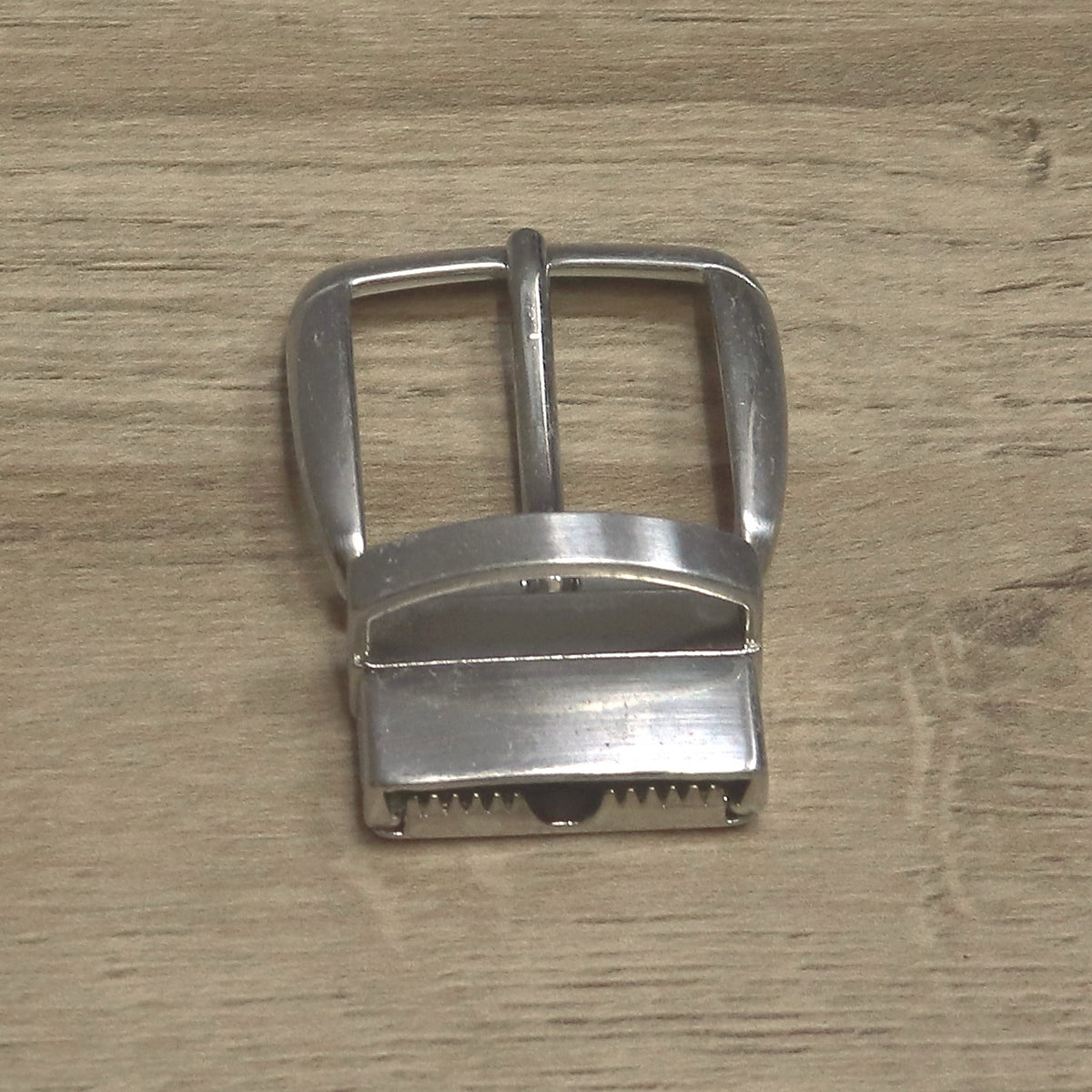Back of a nickel clamp buckle showing the toothed jaw that grips the belt end