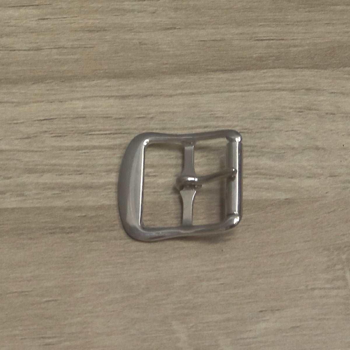 Nickel-plated roller buckle from above, with the broad rounded bar on the left and the roller on the right
