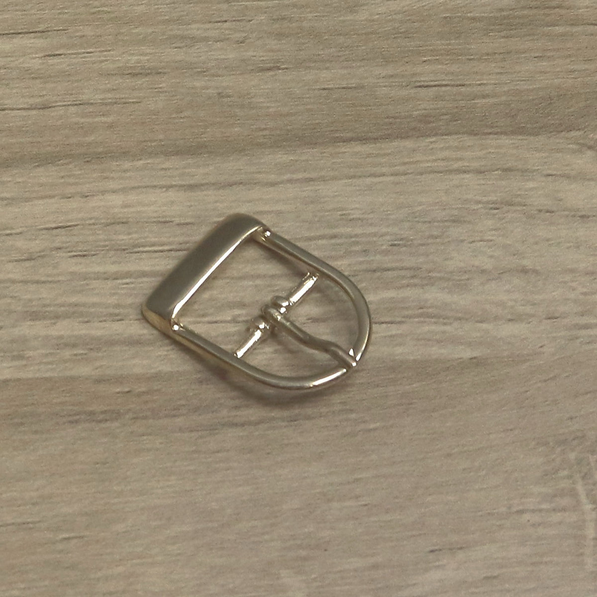 Brass-plated D shape buckle, angled to show the flat heel bar and the pin on the centre bar