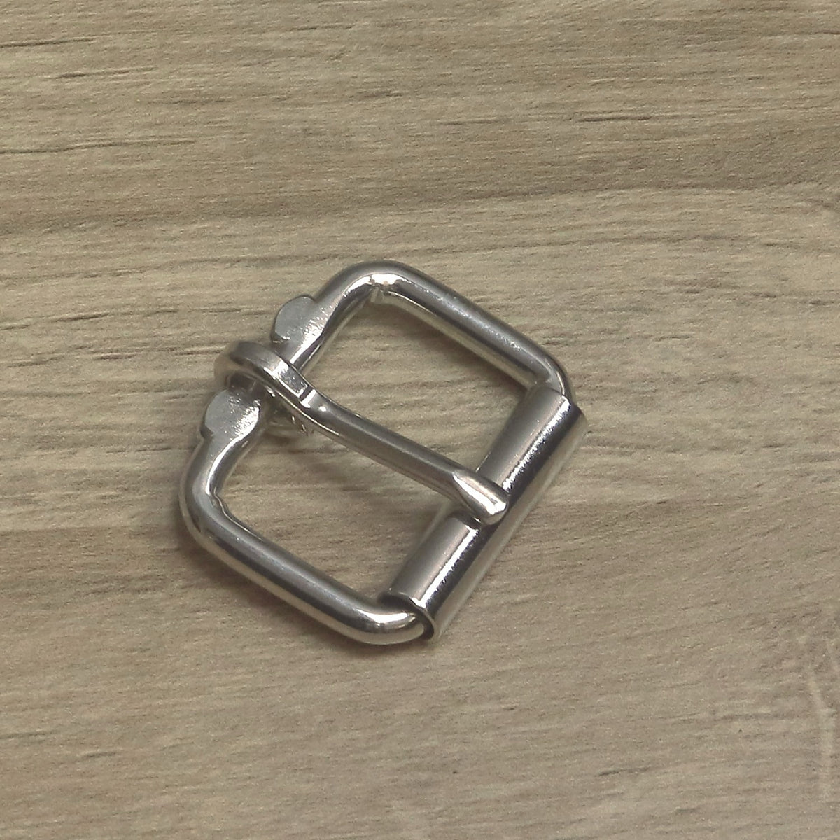 Nickel-plated heavy wire roller buckle at an angle, pin resting on the roller between the two flattened stops