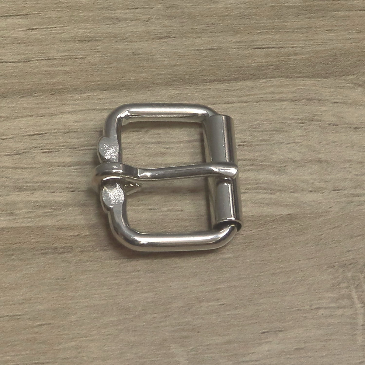 Nickel-plated heavy wire roller buckle from above, pin lying across the frame onto the roller