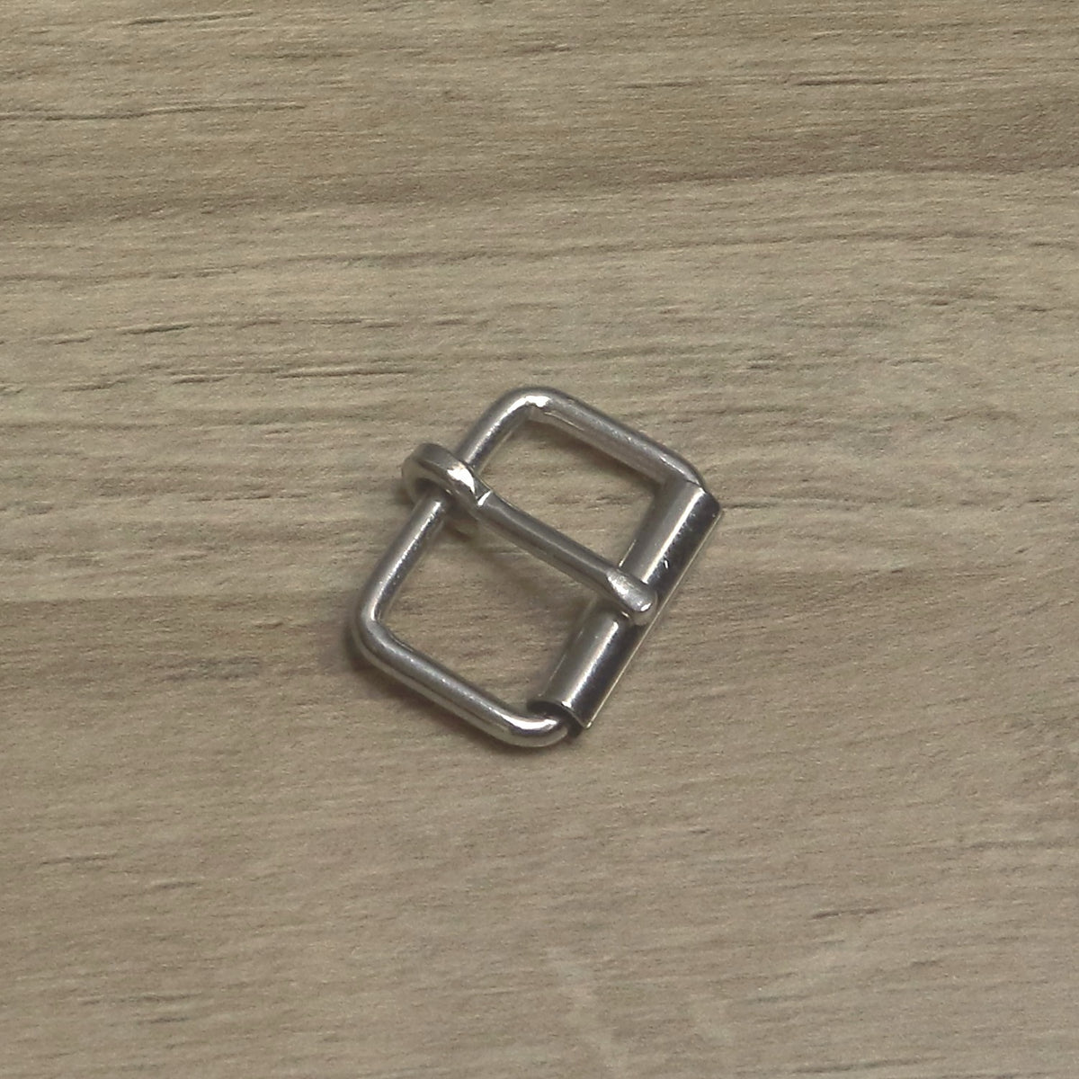 Nickel-plated 25mm wire roller buckle at an angle, pin resting on the roller