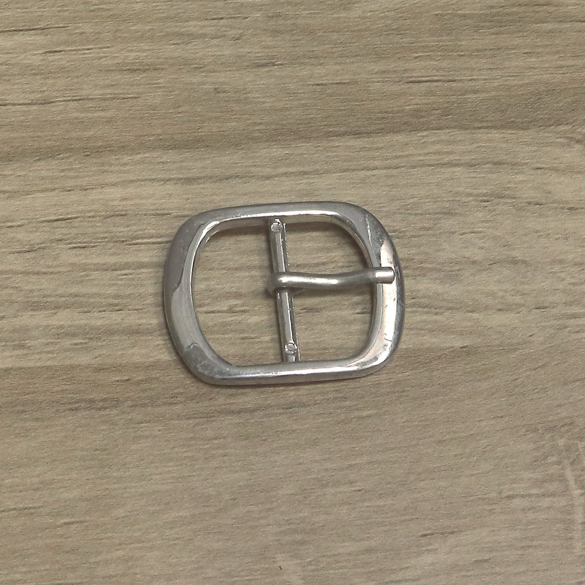 Nickel-plated oval buckle from above, showing the pin on its centre bar