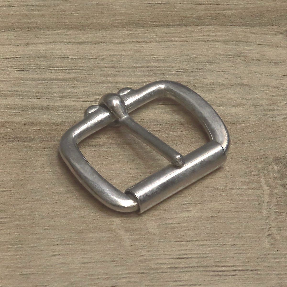 Nickel-plated roller buckle angled to show the pin head and the full-width roller