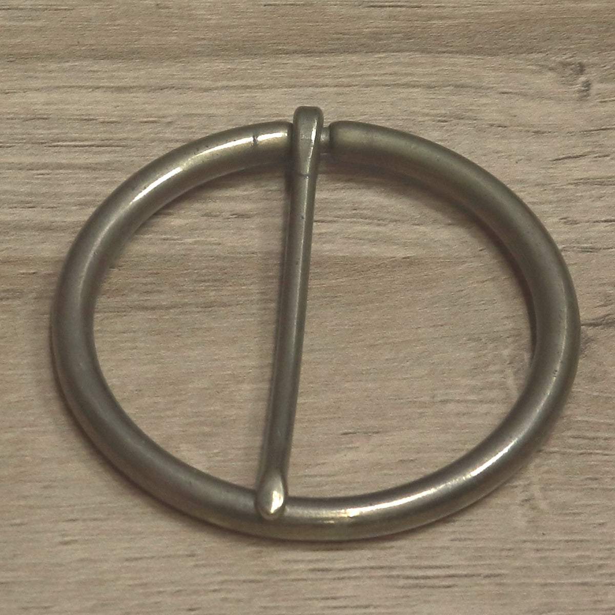 Round buckle angled to show the pin tip resting on the ring