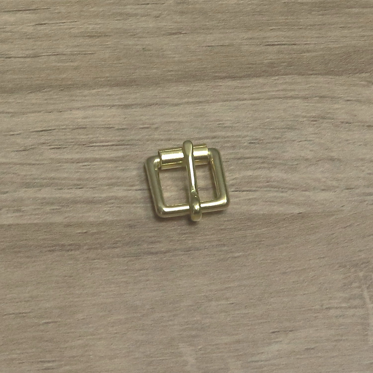 Small brass buckle from above, roller along the top bar and pin pointing up