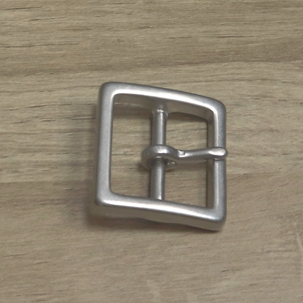 Square cast buckle from above, pin hinged on the centre bar and pointing right