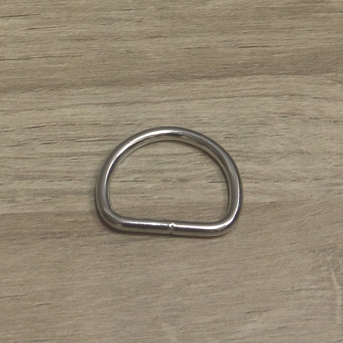 Nickel-plated 30mm welded D ring in 4mm wire, straight side towards the camera showing the join